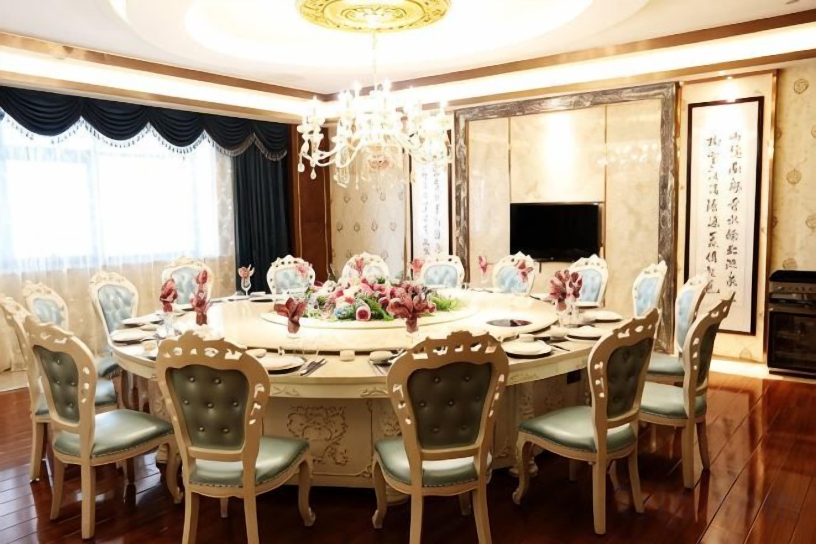 A round dining table with chairs, a chandelier, and floral centerpieces.