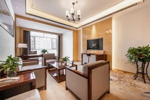 A modern hotel room with a sofa, a desk, a TV, and a large window. - Hezhou Hongrui International Hotel (Linxia)