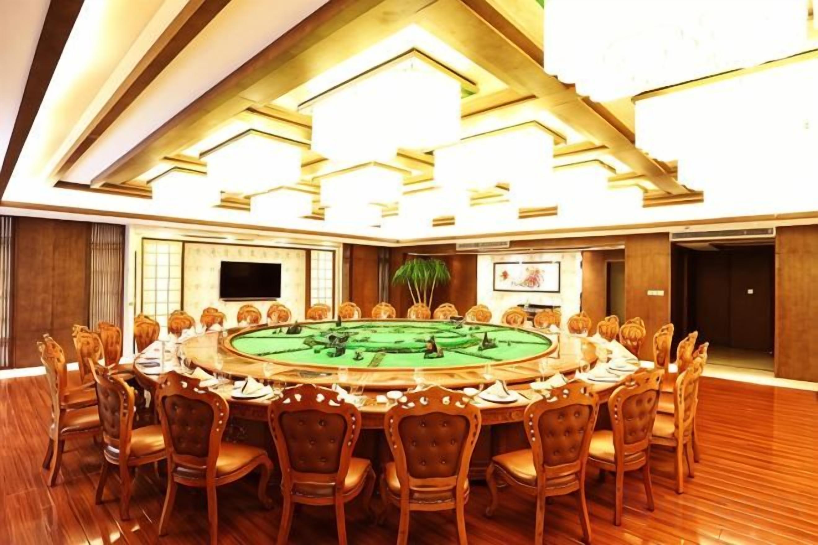 A conference room with a round table, chairs, a television, and a plant.