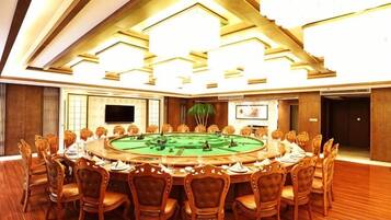 A conference room with a round table, chairs, a television, and a plant.