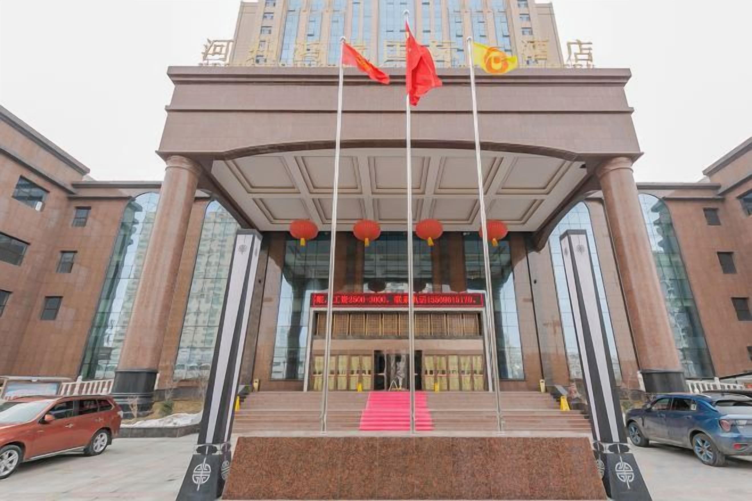A building with a prominent entrance, large windows, and a red flag on a pole.
