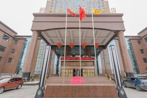 Un edificio con una entrada destacada, amplias ventanas e izada una bandera roja en un asta.