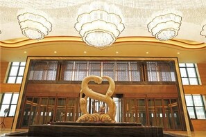 En storslagen entréhall med en stor, dekorativ svanstaty, utsmyckade ljuskronor och ett högt tak.