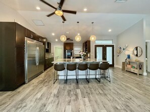 A modern kitchen with a central island, dark cabinetry, stainless steel appliances, and pendant lighting.