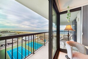 Enjoy the ocean view from this balcony, which offers a comfortable seating area with a chair and a lush plant.