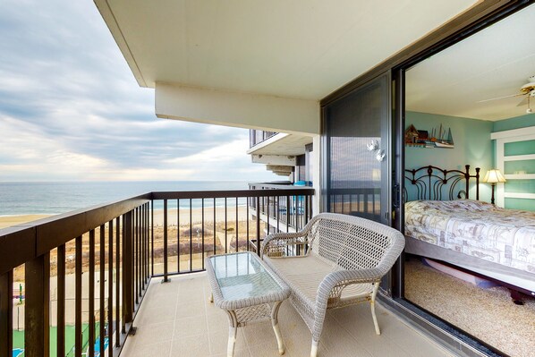 Enjoy a relaxing stay with a balcony overlooking the beach, featuring a wicker chair and small table.
