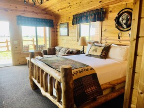 Una habitación de cabaña de madera con una cama, un ventanal y una puerta que da al exterior.