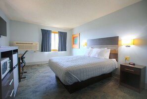 Relax in this inviting room with a comfortable bed, a desk for work, and a window with curtains.