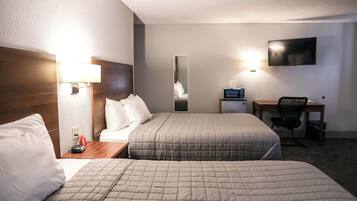 A hotel room with two beds, a desk, a chair, a TV, and a mirror.