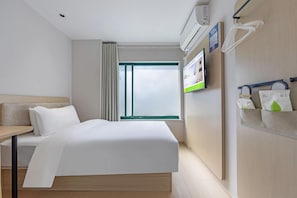 A hotel room with a bed, a desk, a TV, and a wall-mounted shelf with bags. - Hi Inn (Shanghai Zhangjiang Park) (Shanghai)