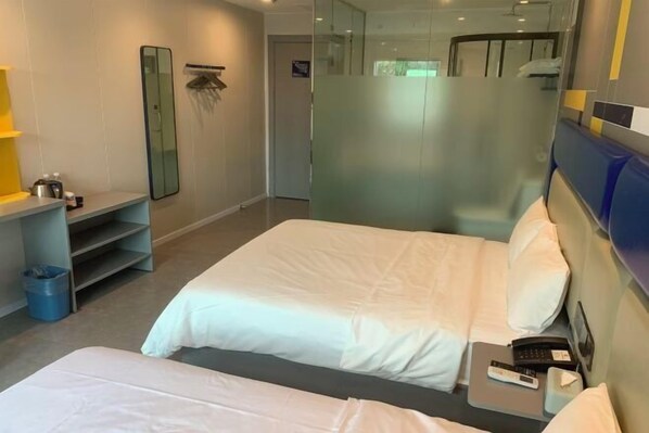 Une chambre d’hôtel avec deux lits, un bureau avec un téléphone et un miroir.