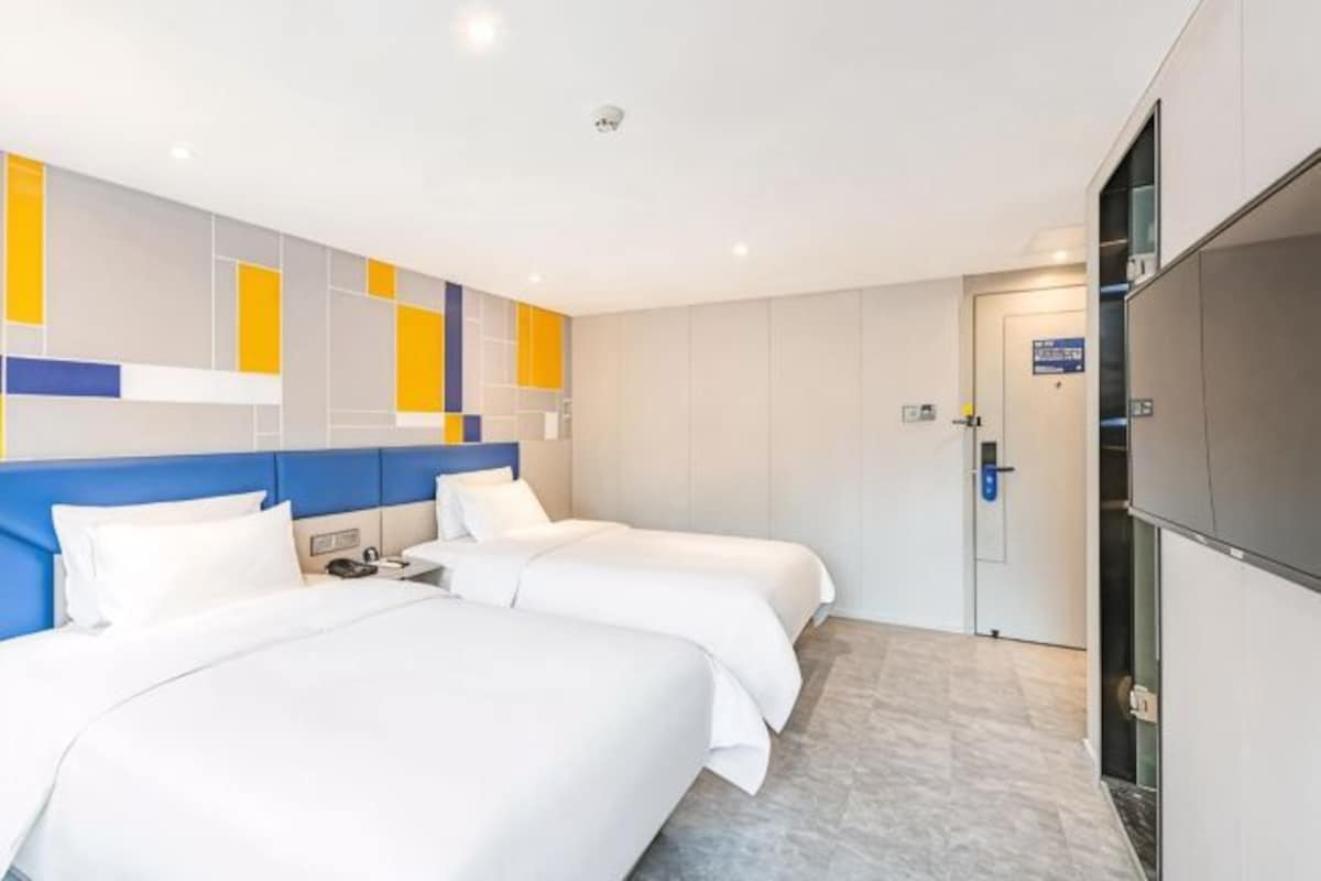 A hotel room with two beds, a TV, and a door leading to a bathroom.