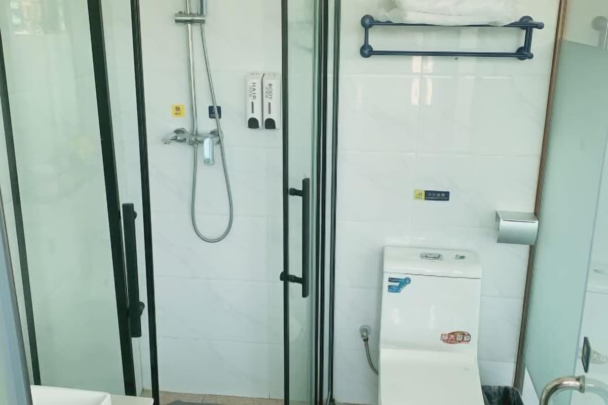 Eine Duschkabine aus Glas mit Handbrause, Bedienfeld und Warmwasserbereiter.