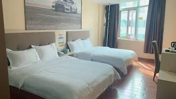 A hotel room with two beds, a desk, a chair, and a window with curtains.