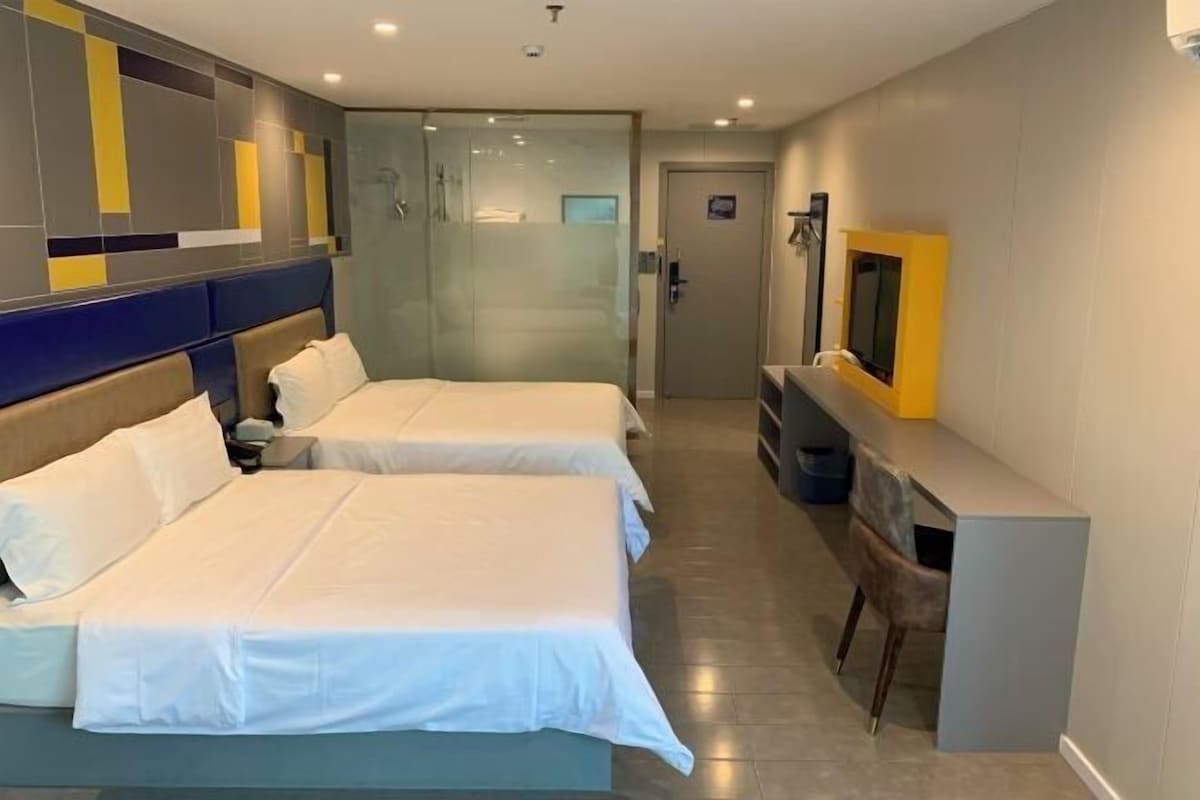 Ein Hotelzimmer mit zwei Betten, einem Schreibtisch und einem Fernseher.