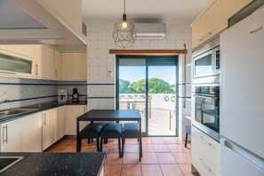 Une cuisine moderne avec un coin repas, un four encastré et une vue sur l’extérieur.
