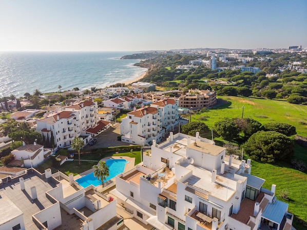 A coastal residential area with white buildings, a swimming pool, and a view of the sea.