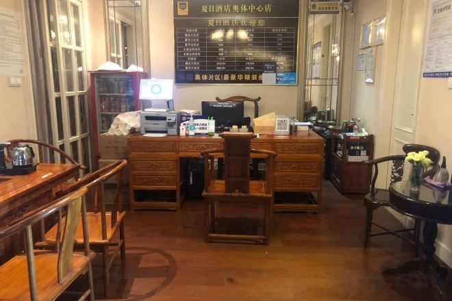 A hotel lobby with wooden furniture, a reception desk, and a menu board.