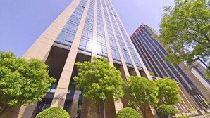 Un edificio alto y moderno con fachada de vidrio y una serie de ventanales verticales.