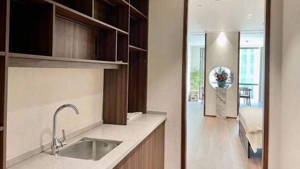 Una cocina moderna con un lavamanos integrado, estanterías de madera y vistas a una sala de estar con balcón.
