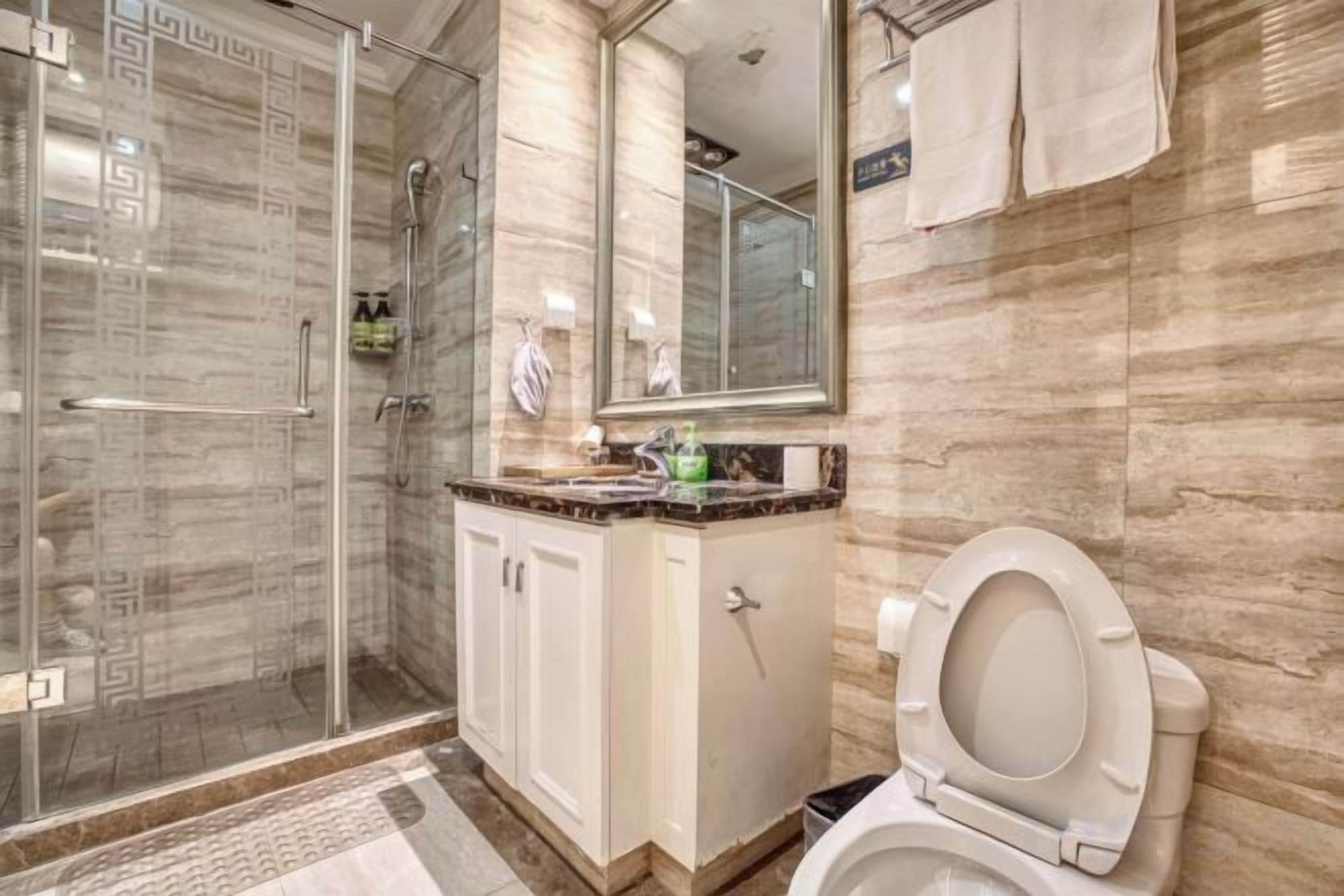 A bathroom with a glass shower enclosure, a toilet, and a vanity with a mirror.