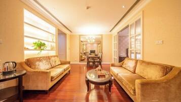 A living room with two sofas, a coffee table, and a dining area in the background.