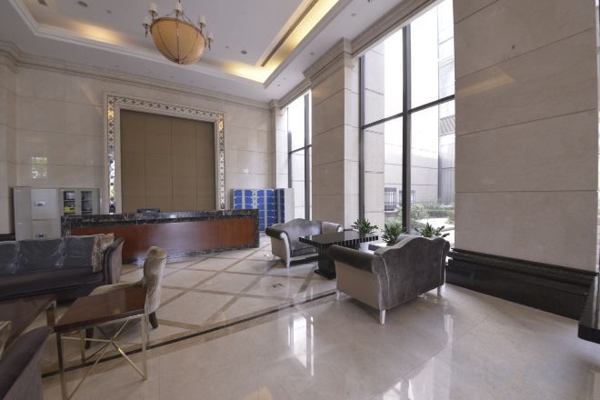 A spacious lobby with a reception desk, seating area, and large windows.