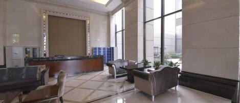A spacious lobby with a reception desk, seating area, and large windows.