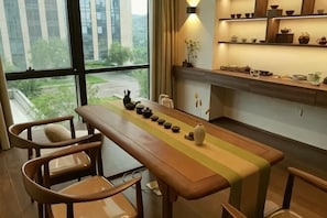 Een eetruimte met een lange tafel, stoelen en uitzicht op het buiten.