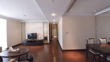 A modern hotel room with a dining area, a flat-screen TV, and a wooden floor.