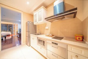 A modern kitchen with a built-in oven, microwave, and stainless steel appliances. - Summer Yulan Apartment (Jinan)