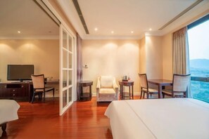 A hotel room with a bed, a desk with a chair, a television, and a view of the outdoors. - Summer Yulan Apartment (Jinan)