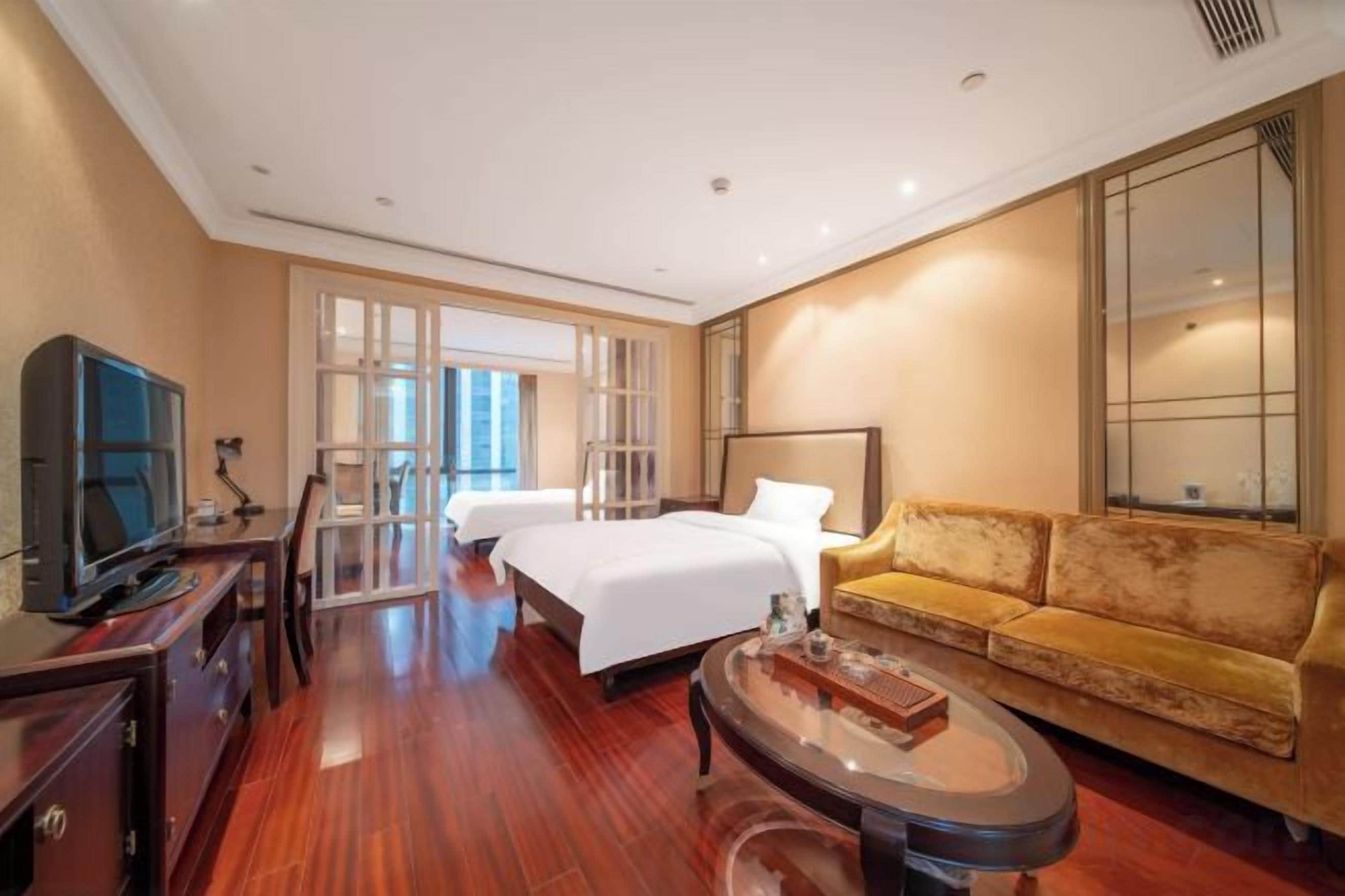 A hotel room with a bed, a sofa, a TV, and a desk.