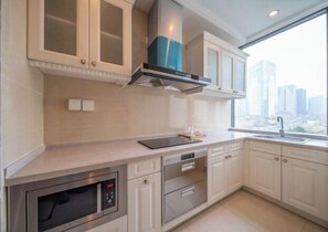 A modern kitchen with a built-in oven, microwave, and a window with a city view.