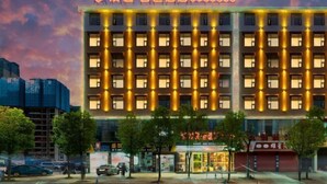 Ett hotell med flera våningar, med en rad likformigt upplysta fönster och en neonreklamskylt ovanför ingången.