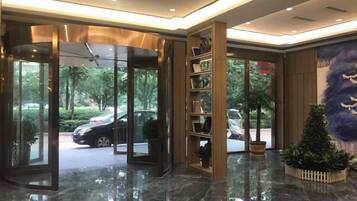 A hotel lobby with a revolving door, a reception desk, and a plant.