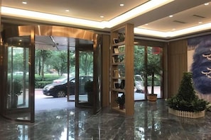 Un hall d’hôtel doté d’une porte tournante, d’un comptoir d’accueil et d’une plante.