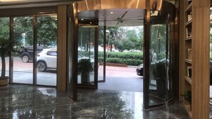 A modern lobby with a revolving door, glass walls, and a polished floor. - Meng Zhi Dao Hotel (Loudi)