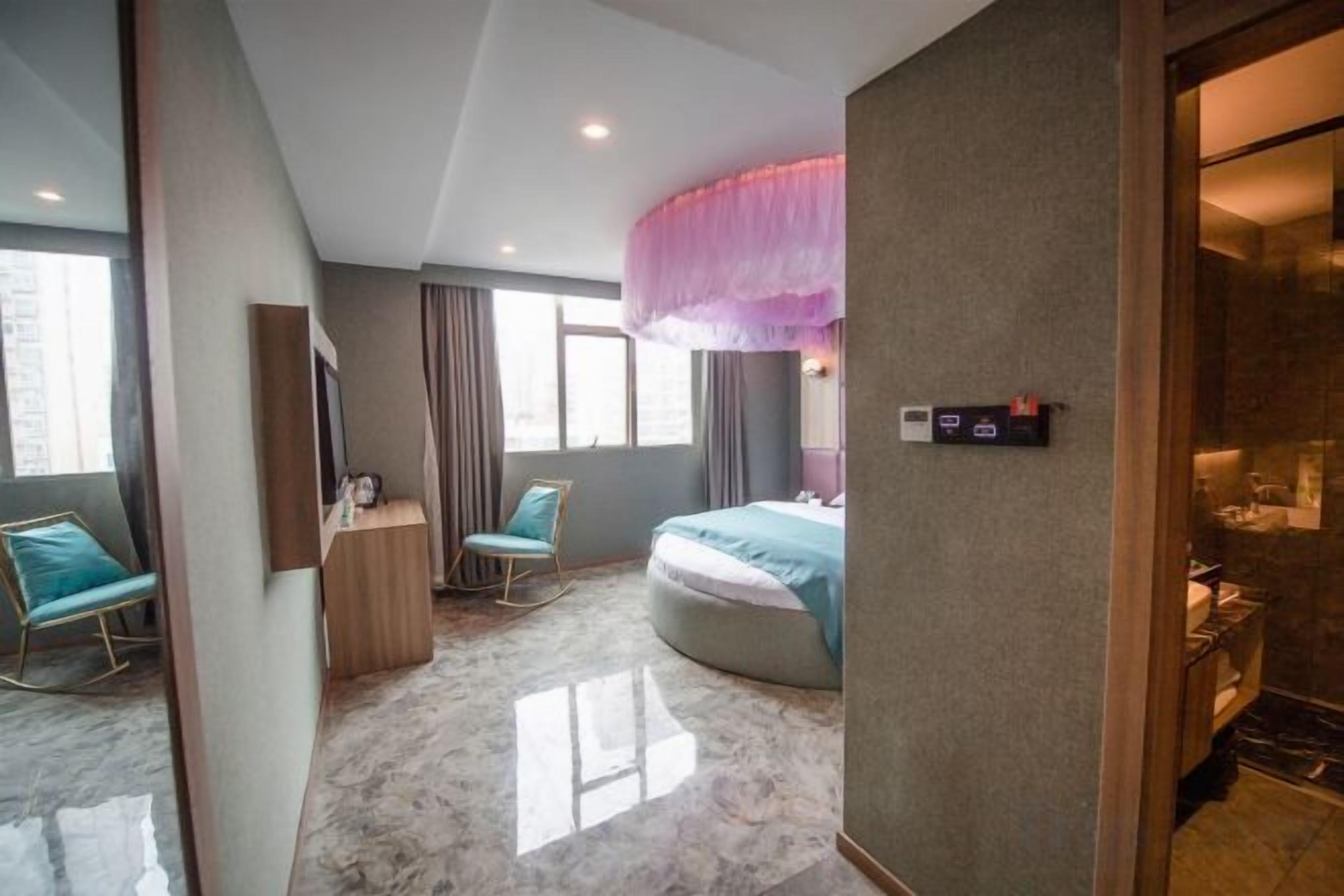 A hotel room with a bed, a desk, a chair, and a bathroom.