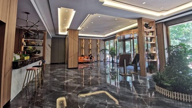 A modern hotel lobby with a polished marble floor, wooden accents, and a seating area with a sofa and chairs. - Meng Zhi Dao Hotel (Loudi)