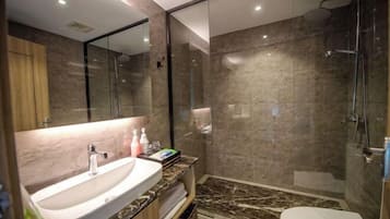 A modern bathroom with a marble sink, a glass shower enclosure, and a toilet.