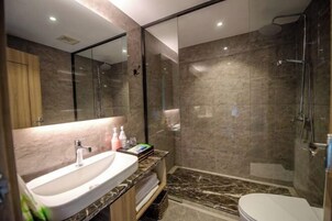 A modern bathroom with a marble sink, a glass shower enclosure, and a toilet.