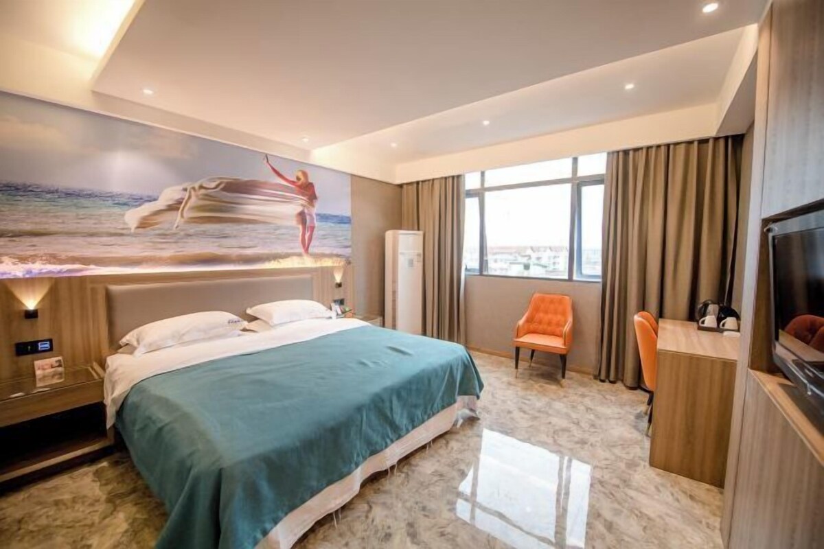 A hotel room with a bed, a desk, a chair, a TV, and a large window with curtains.