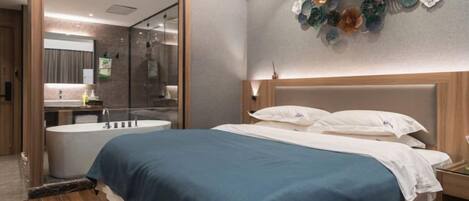 Una habitación de hotel moderna con una cama grande, un baño separado con bañera y un elemento decorativo en la pared.