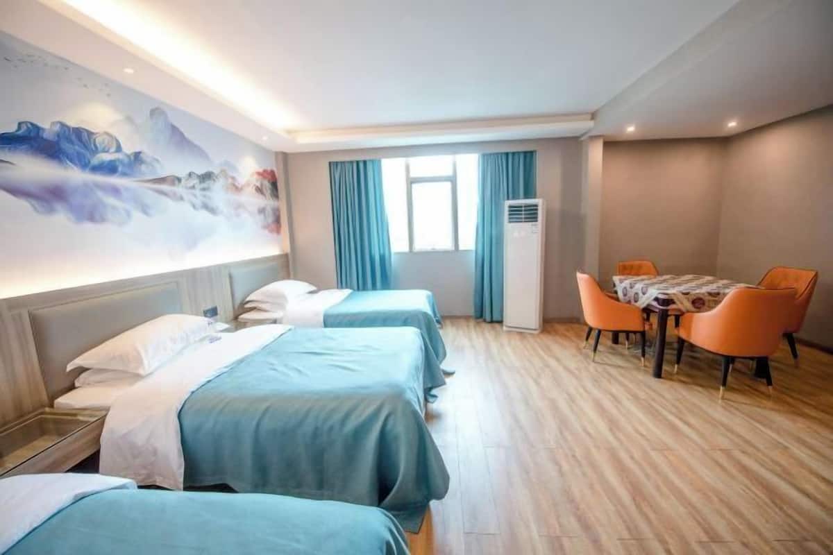 Une chambre d’hôtel avec deux lits, une table à manger avec des chaises, une grande fenêtre avec des rideaux et un climatiseur fixé au mur.