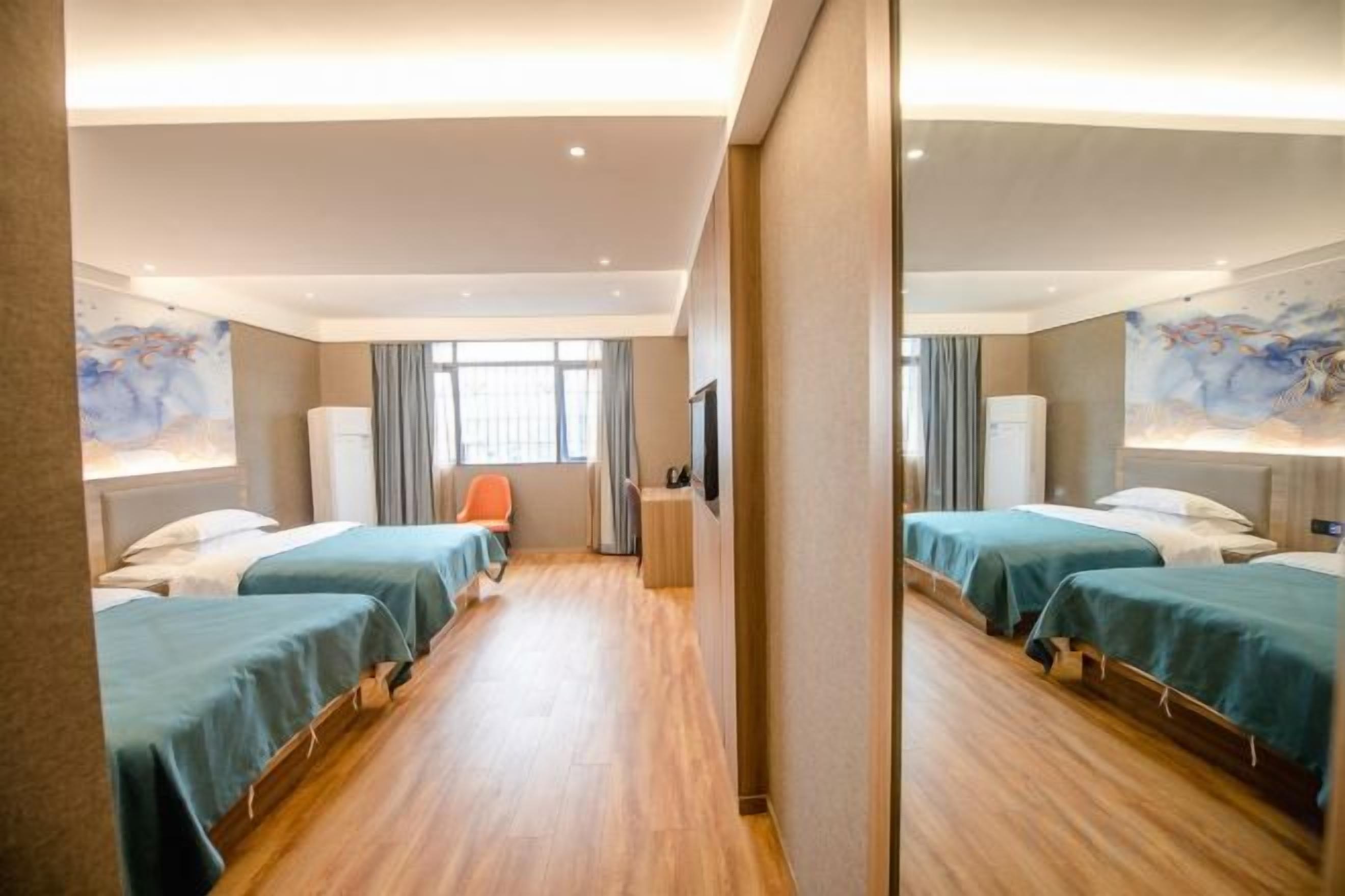 Habitación de hotel con dos camas, un escritorio, una silla y un ventanal grande.