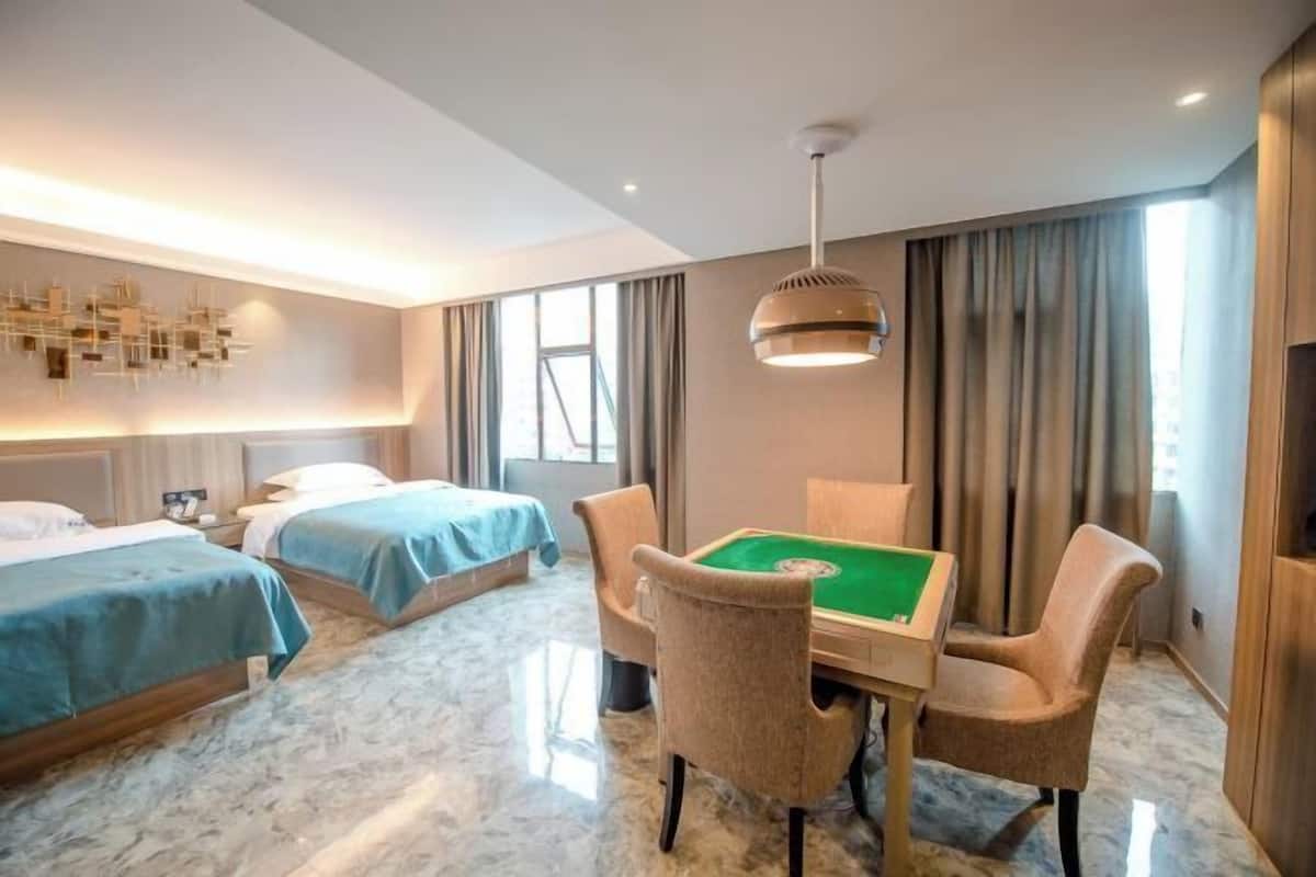 Une chambre d’hôtel avec deux lits, une table de billard et un lustre.