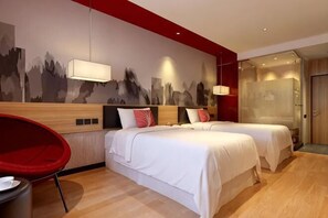 Une chambre dâhĂŽtel avec deux lits, une chaise rouge, une lampe fixĂ©e au mur et une porte.