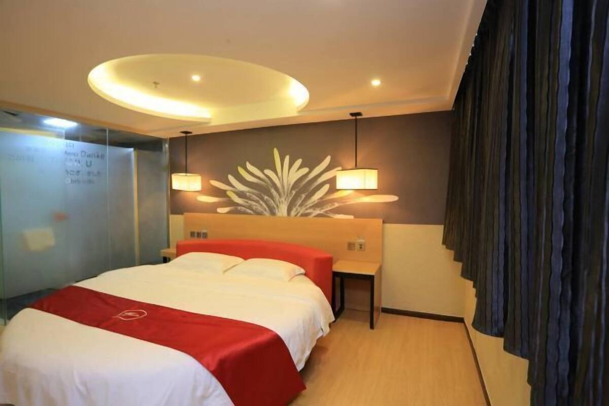 Une chambre d’hôtel avec un lit, des tables de chevet, une lampe fixée au mur et un luminaire au plafond.