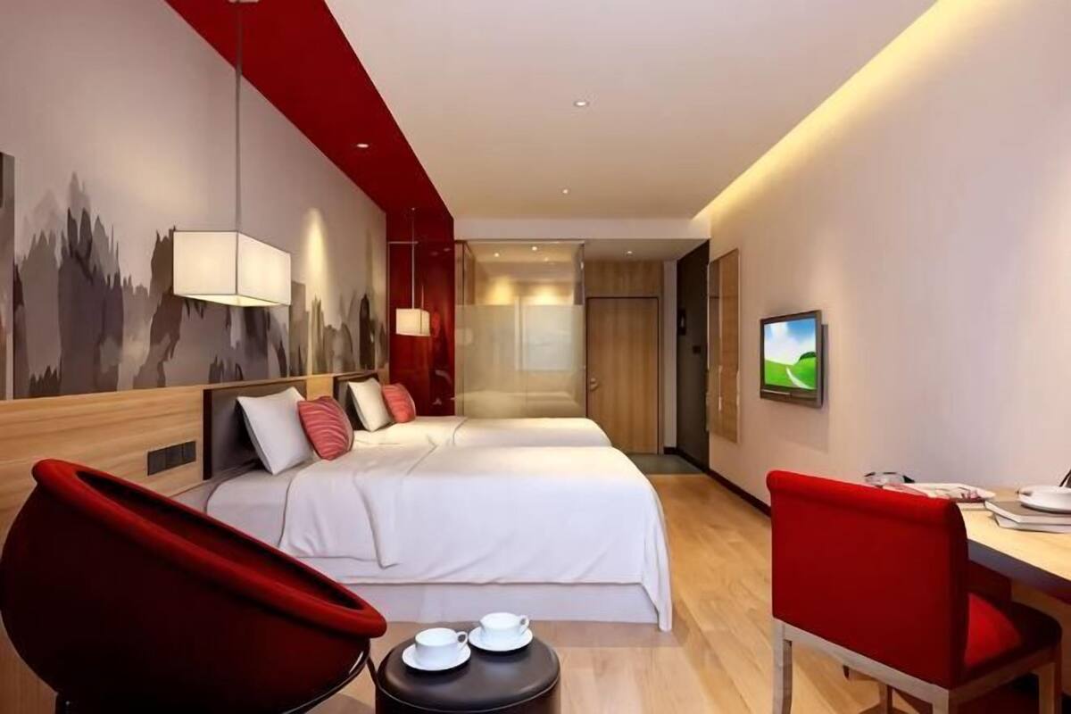 Une chambre d’hôtel avec deux lits, un bureau et une chaise.